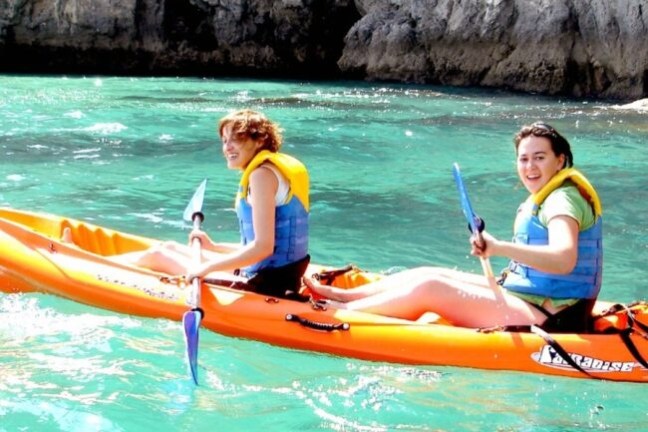 a little girl riding on the back of a boat in the water