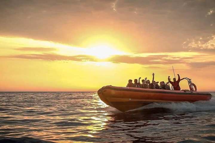 a sunset behind a boat on a body of water