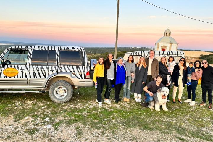 a group of people standing in front of a car posing for the camera