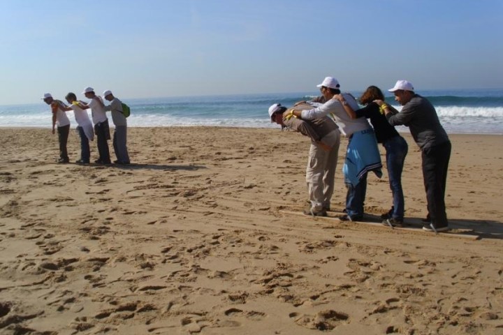 a group of people standing on top of a sandy beach